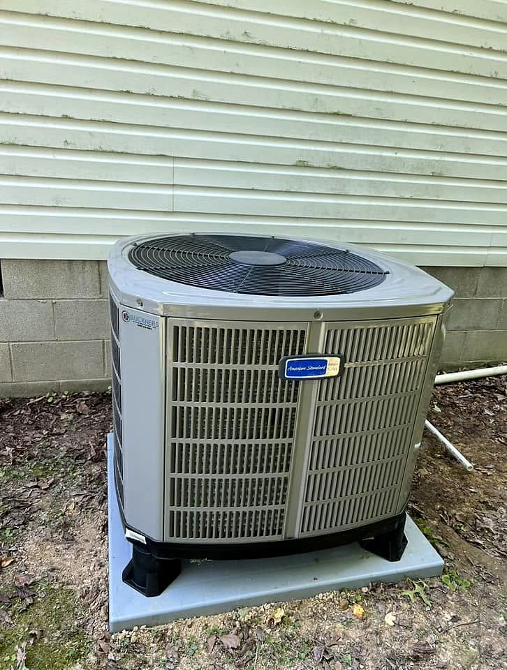 New outdoor condenser with a Buckners sticker on a pad beside a home